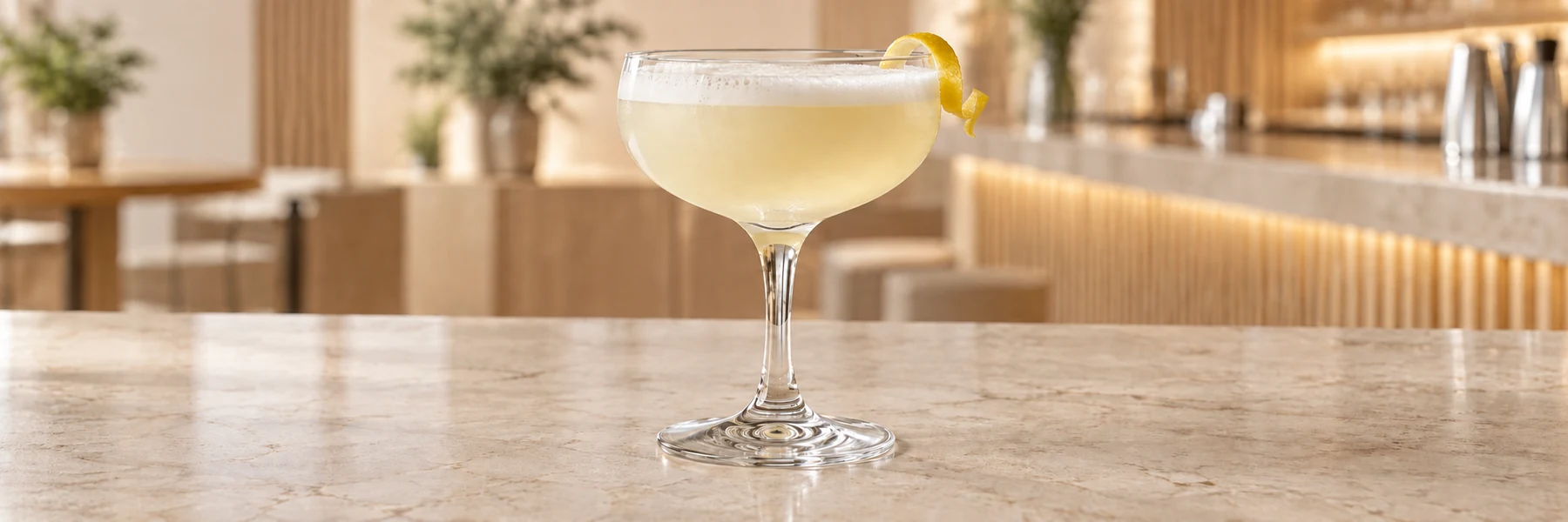 Gin Sour med hvitt skum og sitrontvist i et coupeglass