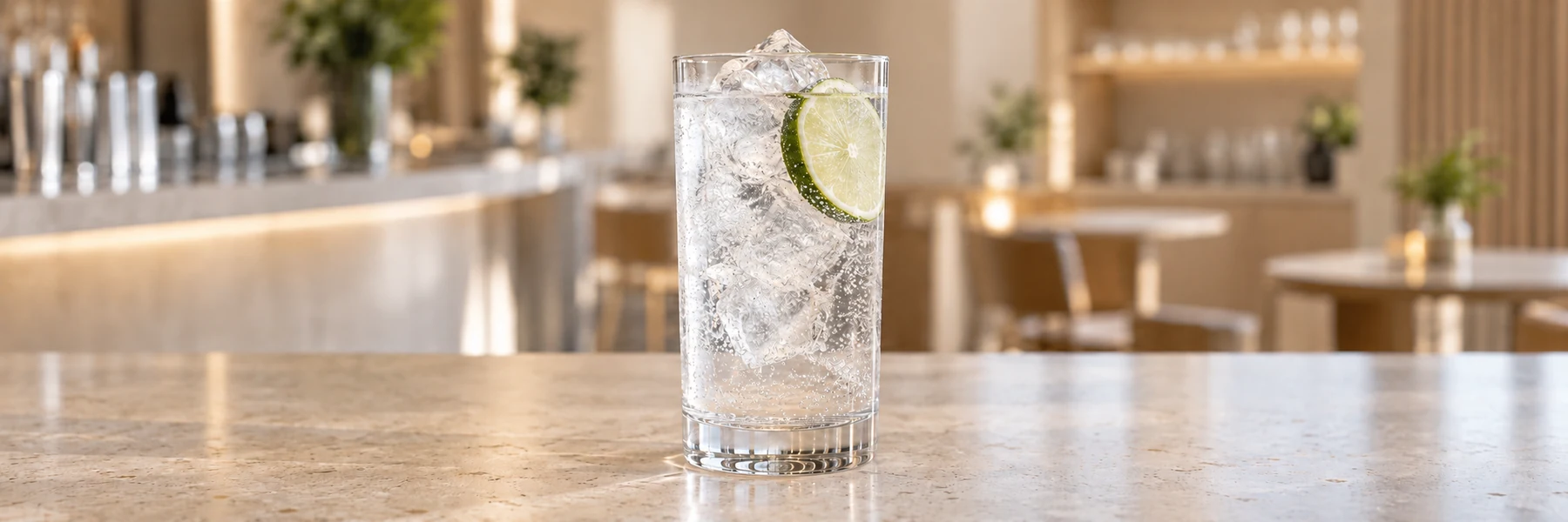 Gin og tonic med is og limeskive i et høyt glass