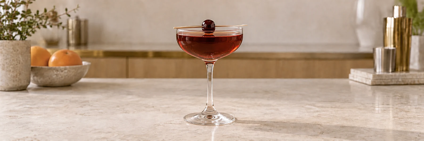 Manhattan i et coupeglass med et mørkt cocktailkirsebær på kanten