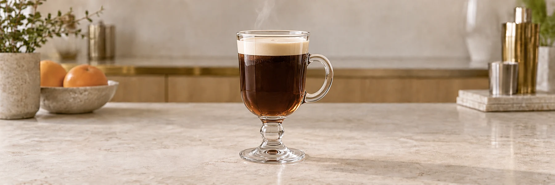 Irish Coffee med mørk kaffe og et lyst lag fløte i et glass med hank og stett