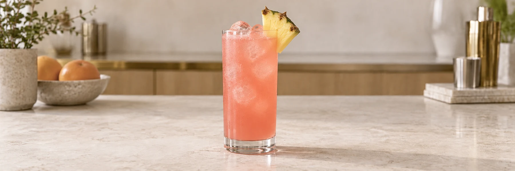 Malibu Bay Breeze med korallrosa juice, is og ananas i et highballglass