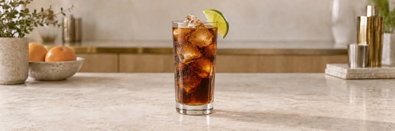 Cuba Libre med cola, klare isbiter og en limebåt i et høyt glass