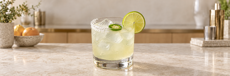 Spicy Margarita med is, halv saltkant, lime og jalapeño i et lavt glass.